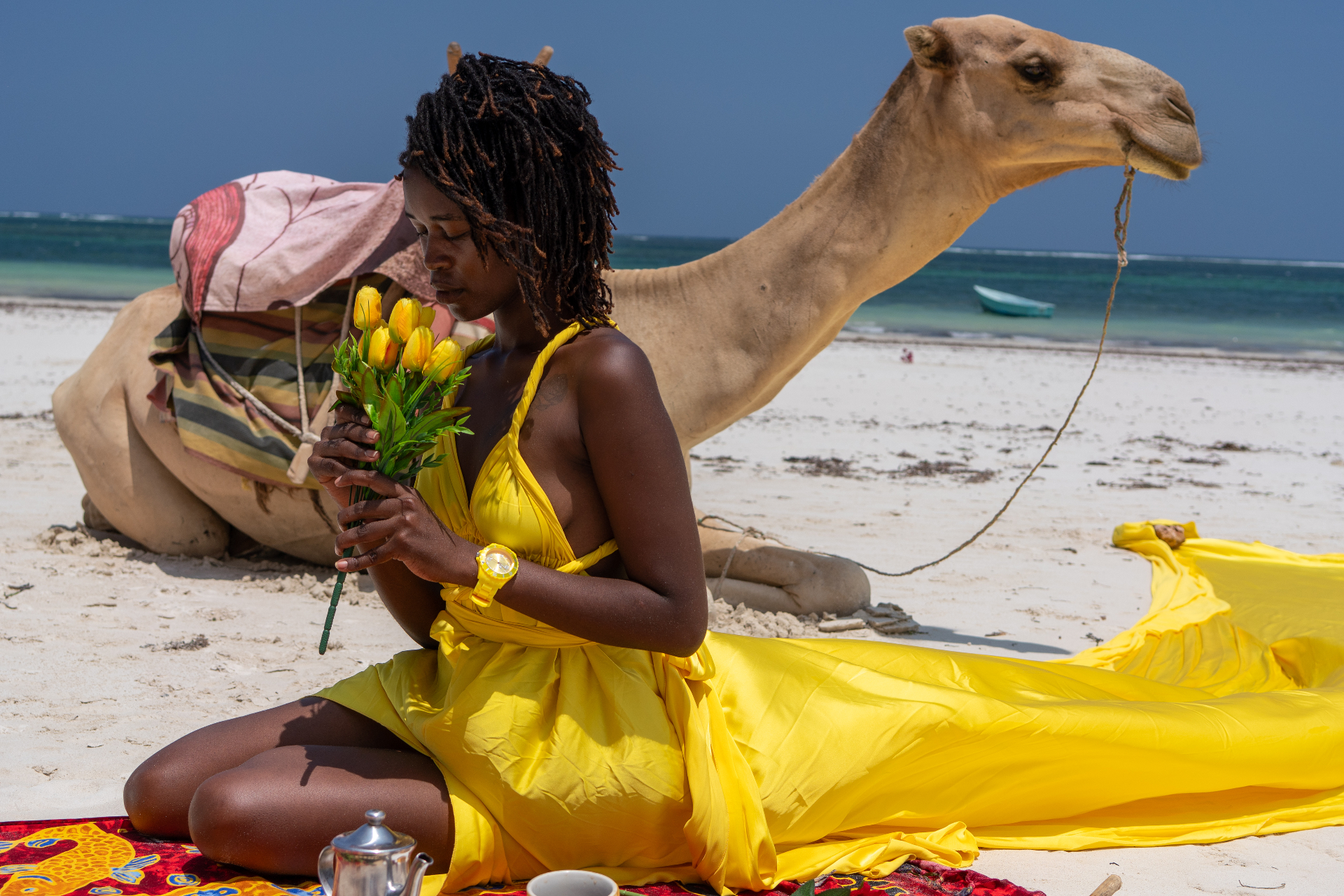 Woman in a yellow flying dress with a camel on the beach