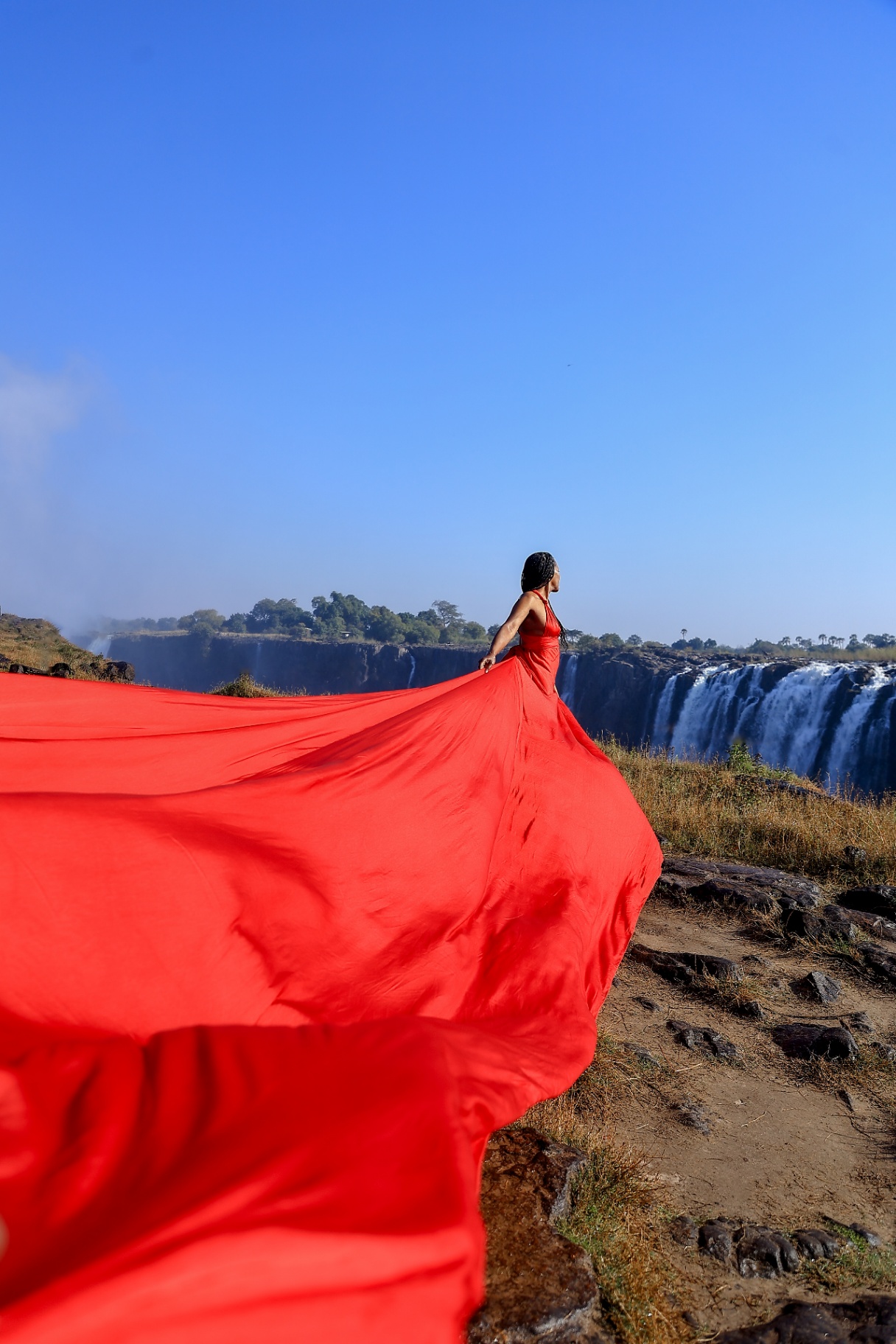 Red flying dress caught by the wind with the falls thundering behind
