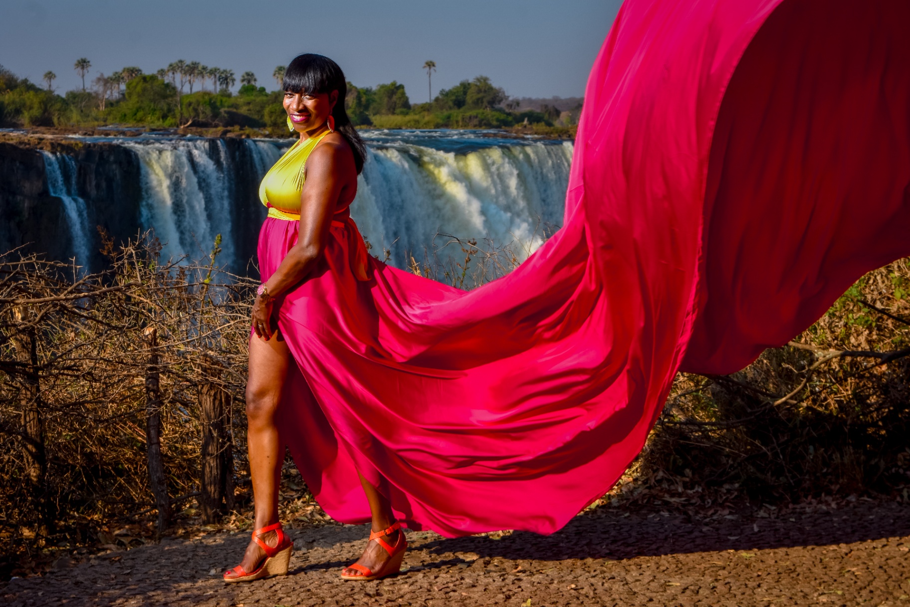 Magenta and gold flying dress sweeping wide with the falls behind