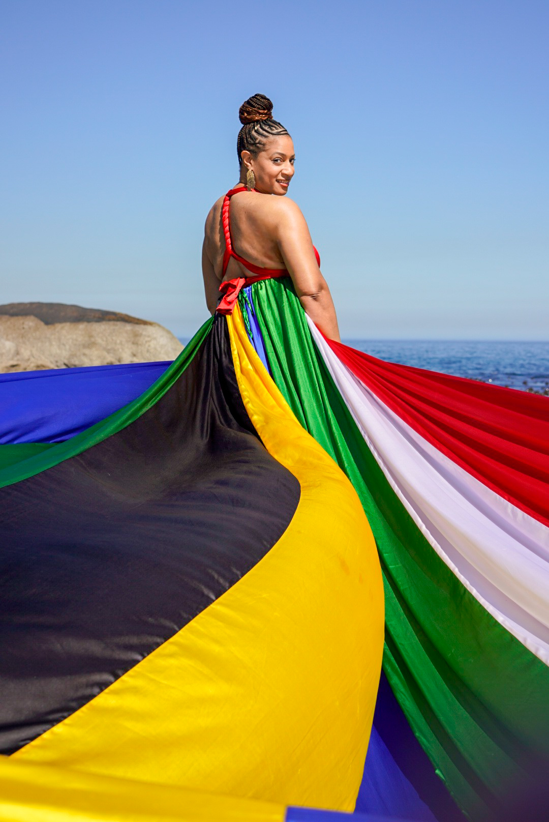 Woman in a flowing multicolour dress beside the ocean