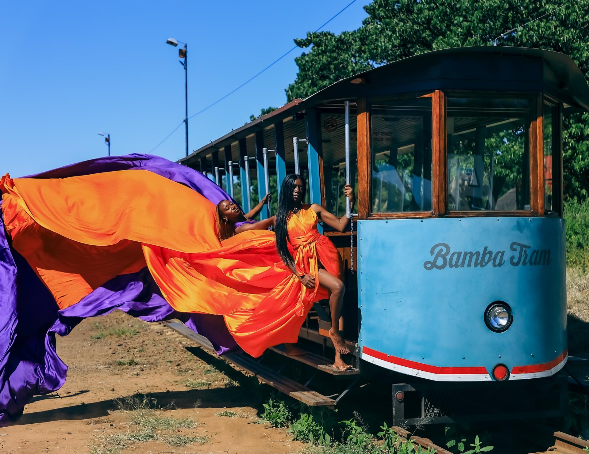 Orange and purple flying dresses aboard the Bamba Tram in Victoria Falls town