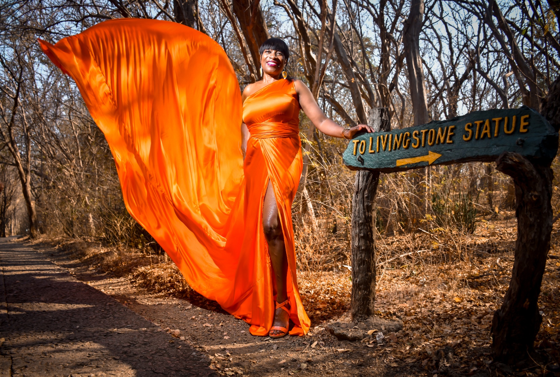 Orange flying dress beside the To Livingstone Statue sign on the falls path